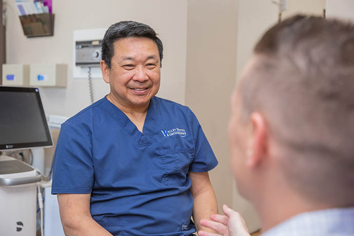 Dr. Doug Wong smiles to a male patient in front of him